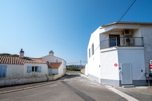 Eine ruhige Straße mit zwei Gebäuden, wobei eines einen Balkon und eine Tür mit der Aufschrift 'NO 1' hat.