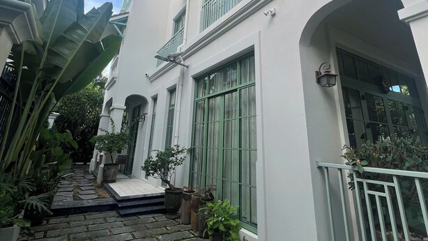 A white building with green window frames and a stone pathway leading to the entrance. - M Signature Tropical Villas Phu Quoc (Phu Quoc)