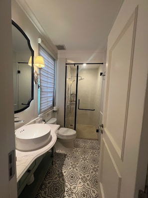 Un baño compacto con lavamanos, inodoro y zona de ducha con puerta de cristal.
