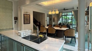 A spacious kitchen with a large island, a dining area with chairs, and a staircase leading to another level. - M Signature Tropical Villas Phu Quoc (Phu Quoc)