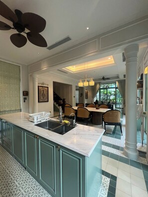 Una cocina amplia con una isla grande, un comedor con sillas y una escalera que lleva a otro nivel.