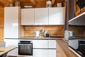 Eine moderne Küche mit weißen Schränken, einem Einbauofen, einer Kaffeemaschine und einem Wasserkocher auf der Arbeitsplatte.