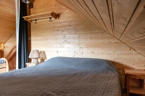 Et rum med træpaneler, en seng, en lampe og en reol.