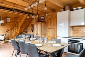 A wooden interior with a dining area, kitchen, and a staircase.