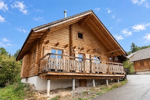 Eine Holzchalet mit Balkon, Schornstein und kleinem Fenster.