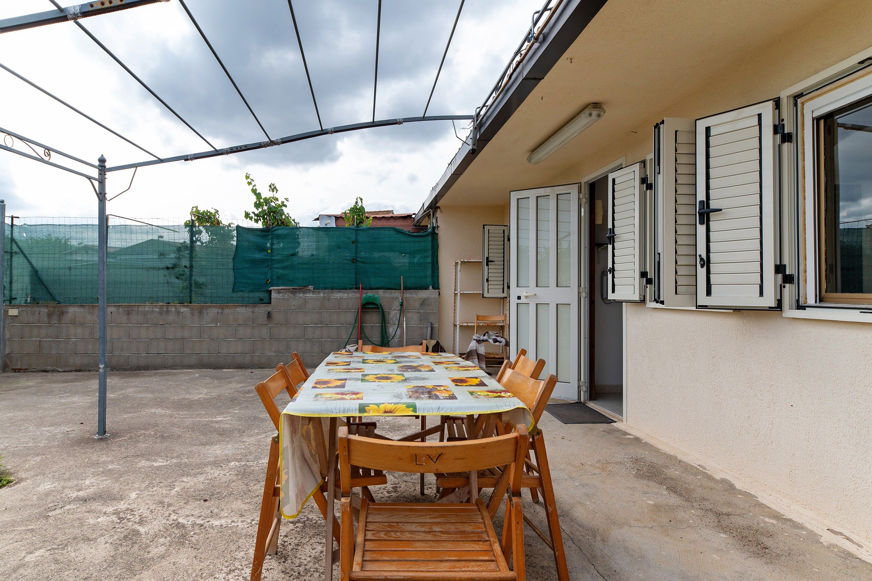 An outdoor patio with a table set for dining, surrounded by chairs.