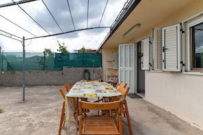 An outdoor patio with a table set for dining, surrounded by chairs.