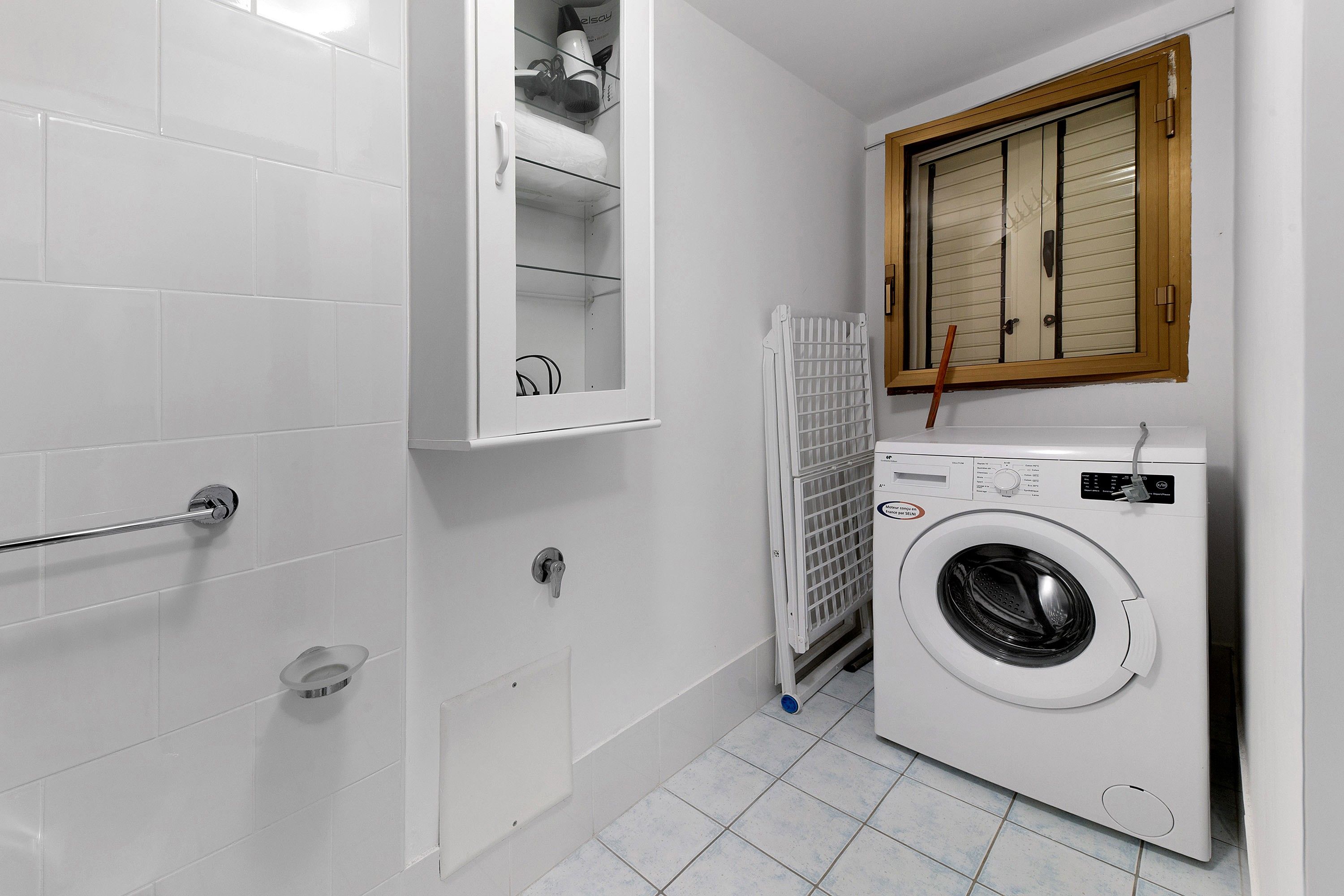 Een kleine badkamer met een ingebouwde wasmachine, een handdoekhouder en een radiator.