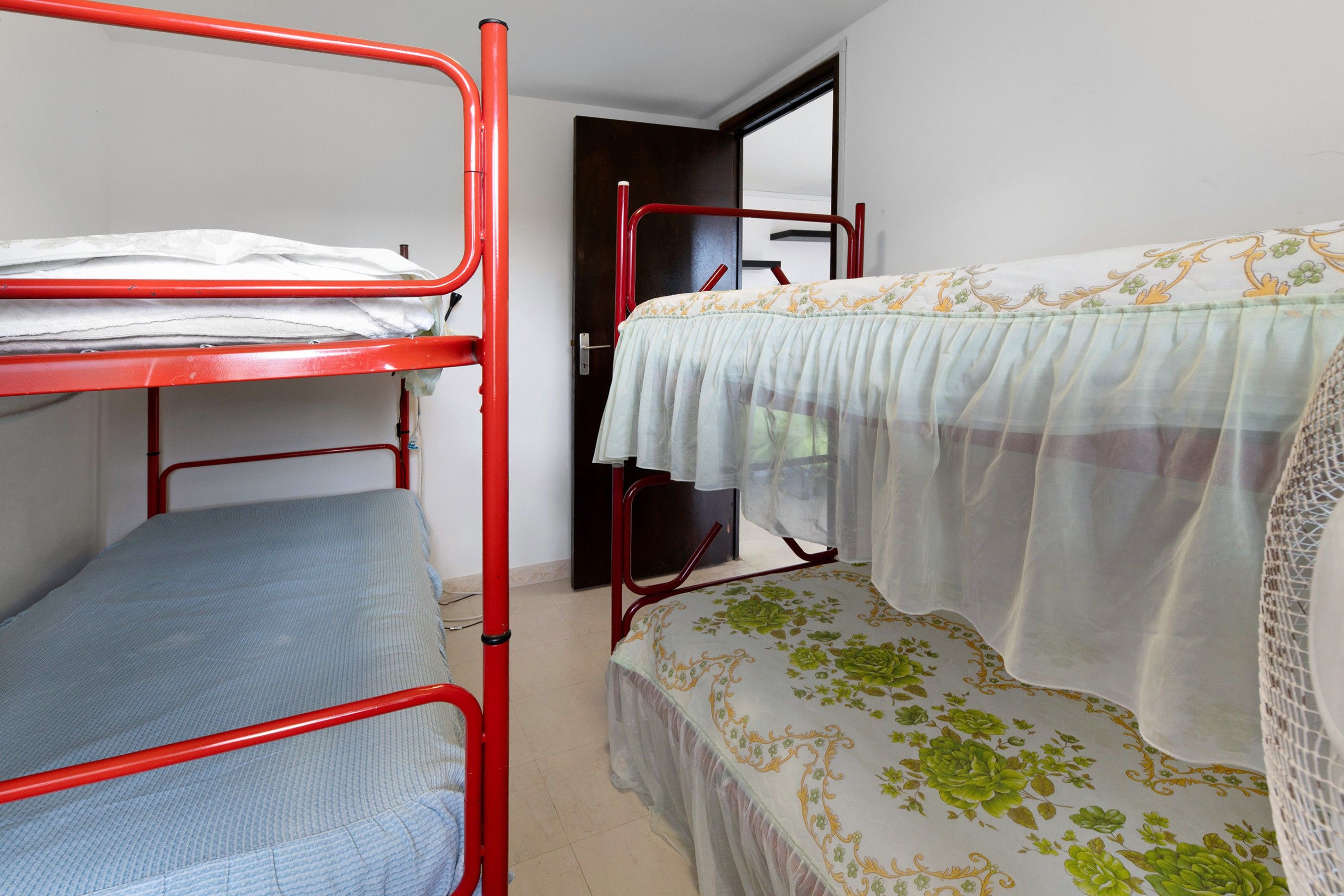 A dormitory room with bunk beds, a door, and a window.