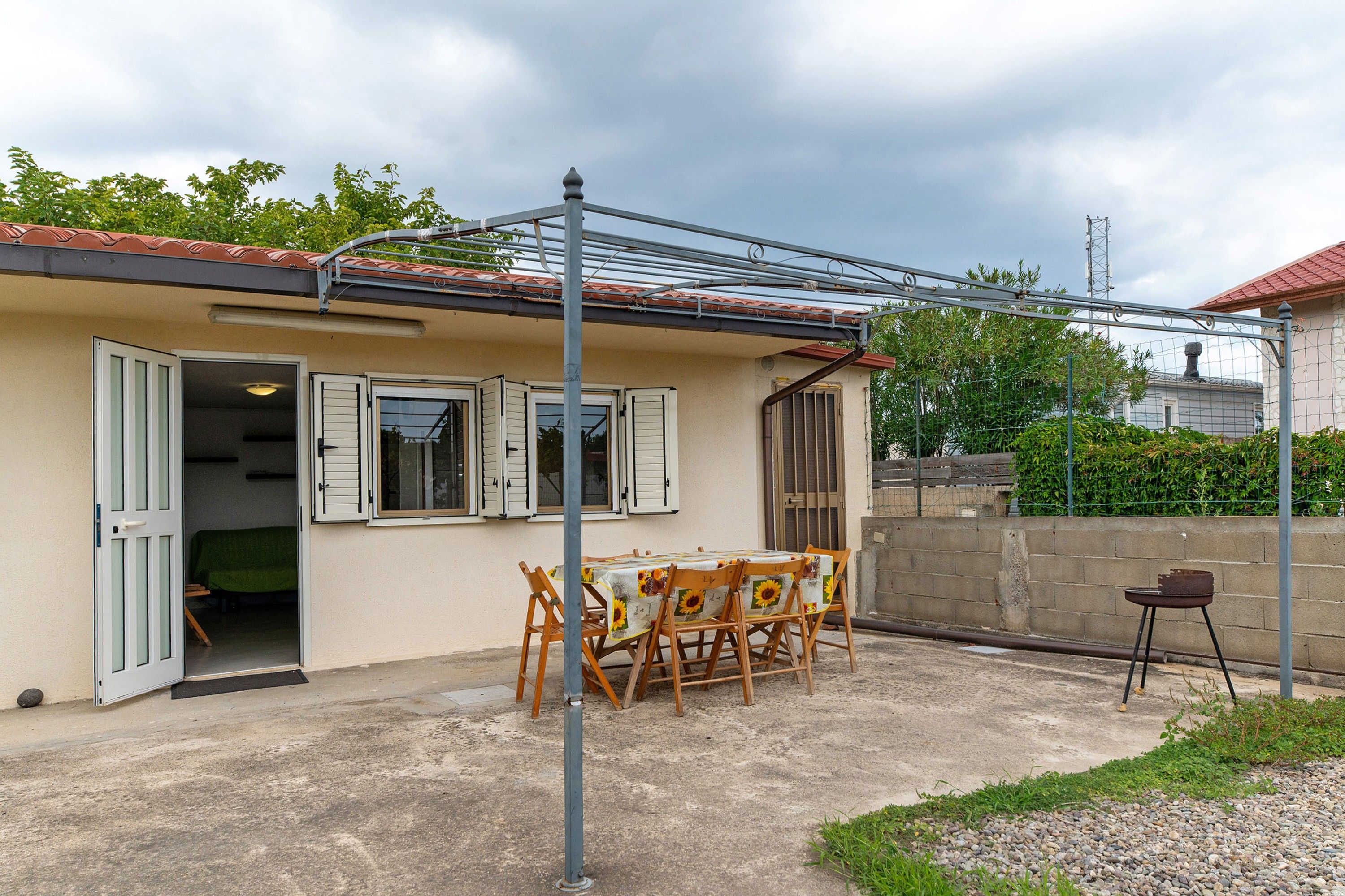 Un edificio de una planta con un patio cubierto, una mesa con sillas y un pequeño espacio de estar al aire libre.