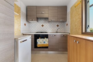 Kompakti keittiö, jossa on puukaapit, sisäänrakennettu uuni ja ikkuna.