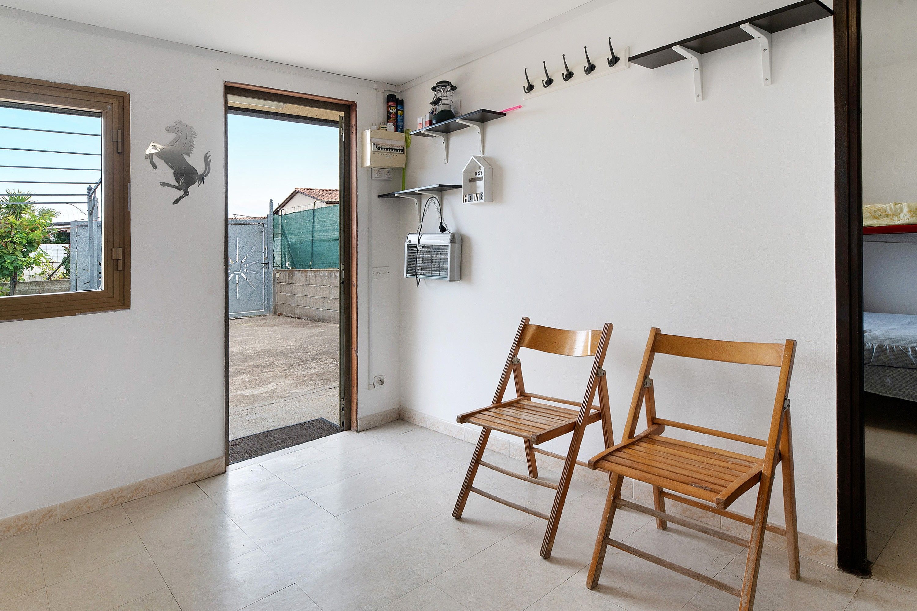 A room with a door leading outside, a window, a radiator, and a chair.