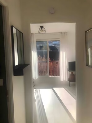 En korridor som leder ut till en balkong med utsikt över en byggnad och ett staket.