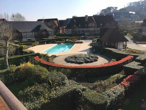 A residential area with a swimming pool surrounded by well-manicured gardens and traditional houses. - Holiday Home '2 Pièces À Deauville Avec Piscine' with Wi-Fi (Deauville)