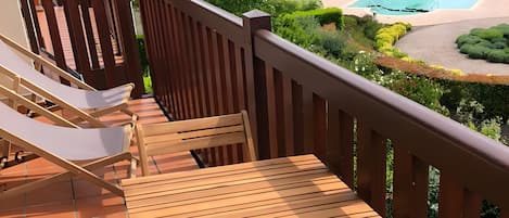 A wooden deck with outdoor seating and a view of a swimming pool.