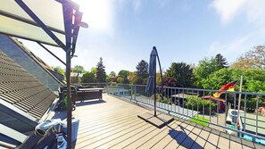 A wooden deck with a grill, outdoor furniture, and a flag.