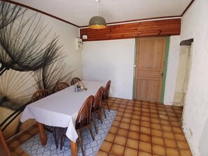 A dining area with a white table, wooden chairs, a hanging light fixture, and a tiled floor. - La Maison du Bonheur 20 -seat (Plassac)