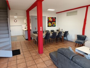 Een moderne woonkamer met een eetgedeelte, rode accenten en een keuken op de achtergrond.