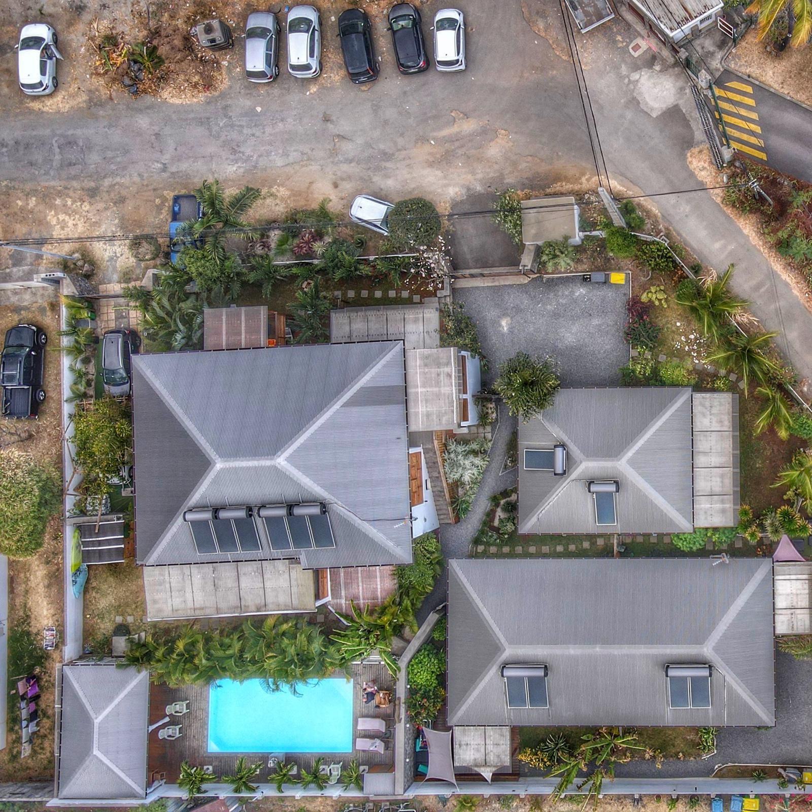 A residential area with multiple houses, a swimming pool, and parked cars.