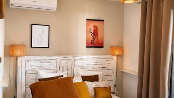 Habitación de hotel con cama, aire acondicionado de pared, un cartel y una lámpara colgante.