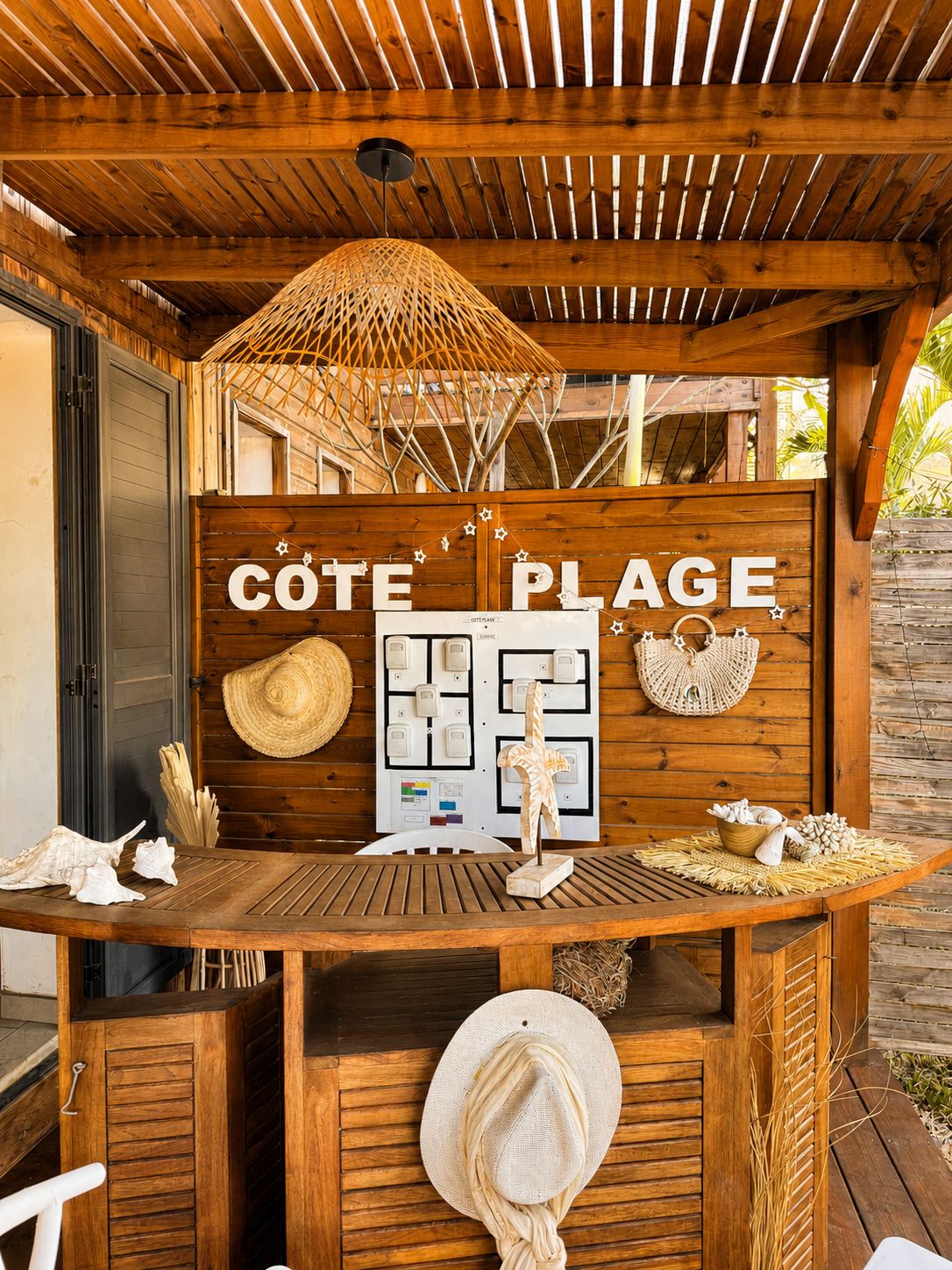 A wooden outdoor seating area with a sign reading 'CÔTE PLAGE' and a control panel with lights.
