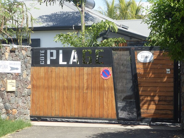 Una entrada con portón y un letrero que dice 'COTE PLAGE' y un letrero de 'prohibido estacionar'.