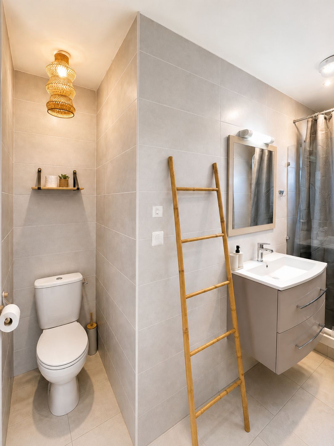 Un baño con inodoro, lavamanos, espejo, cortina de ducha y una escalera de madera.