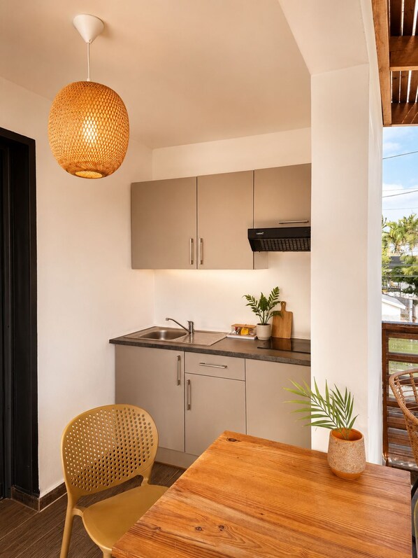 Una cocina moderna con estufa integrada, un lavaplatos y una mesa de comedor de madera con una silla.