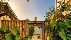 A wooden gate with a decorative arch, surrounded by lush green plants. - Côté Plage (Saint-Paul)