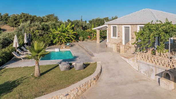 A pool area with lounge chairs, a stone building, and a garden with various plants. - Binios Villa - private pool, walking distance from the Beach (Ano Vasilikos)