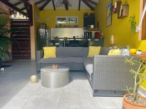 A living room with a grey sofa, yellow cushions, a round metal table, and a potted plant. - CITRONNELLE, a cozy setting with its own private pool. (Le Diamant)