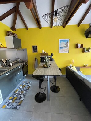 Une cuisine avec une table à manger, des chaises et un luminaire suspendu.