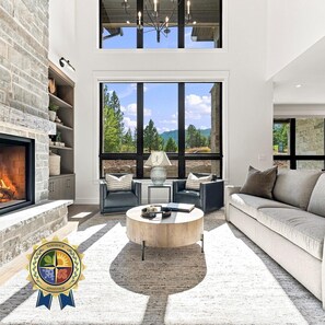 A modern living room with a fireplace, large windows, and a stone wall. - Everpine Haus | Exclusive Tamarack Perks (Tamarack)