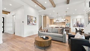 A modern living room with a grey sofa, a round wooden coffee table, and a black leather sofa.