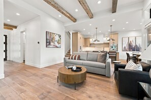 Ein modernes Wohnzimmer mit einem grauen Sofa, einem runden Holztisch und einem schwarzen Ledersofa.