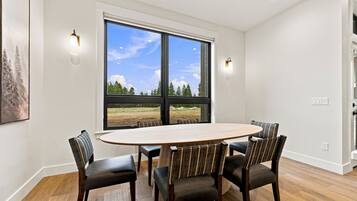 A dining area with a large oval table, four chairs, and two wall-mounted lights.