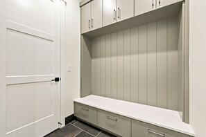 Ein begehbarer Kleiderschrank mit einer weißen Tür, einer Arbeitsplatte und Schubladen.
