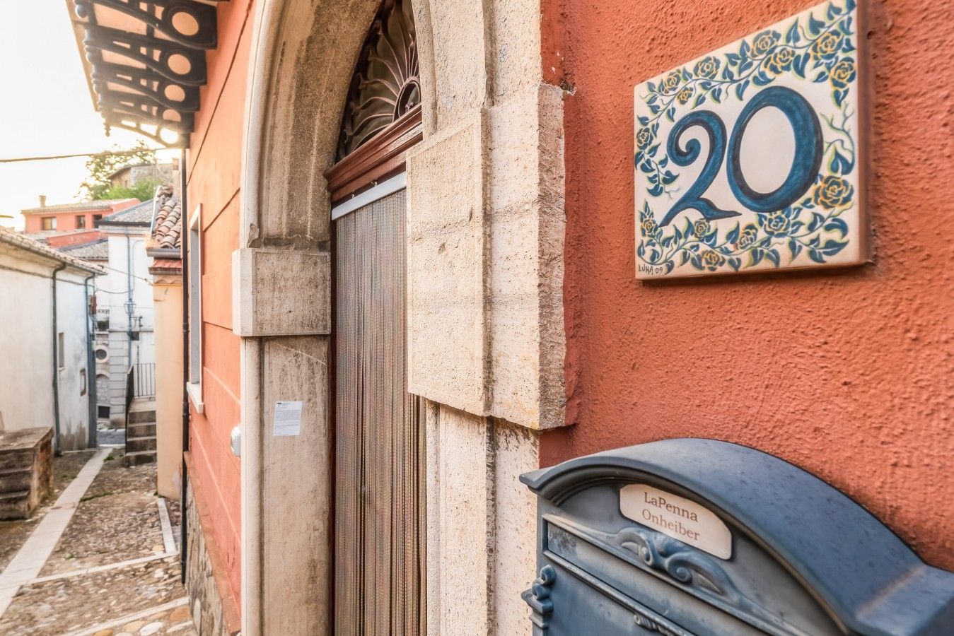 A building corner with a door, a mailbox, and a number plate.