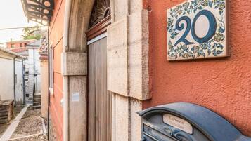 A building corner with a door, a mailbox, and a number plate.