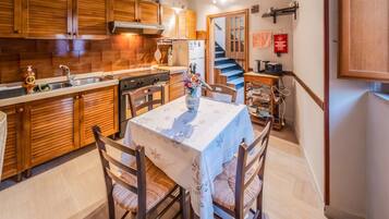 Une cuisine avec des meubles en bois, une table à manger avec des chaises et un escalier menant à un autre niveau.