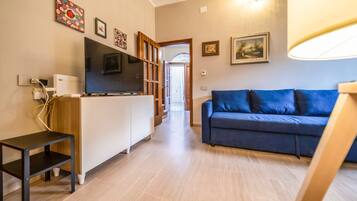 Uma sala de estar com sofá, TV e um armário de madeira.