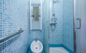 A bathroom with a white sink, a towel hanging on a rack, and a shower area.