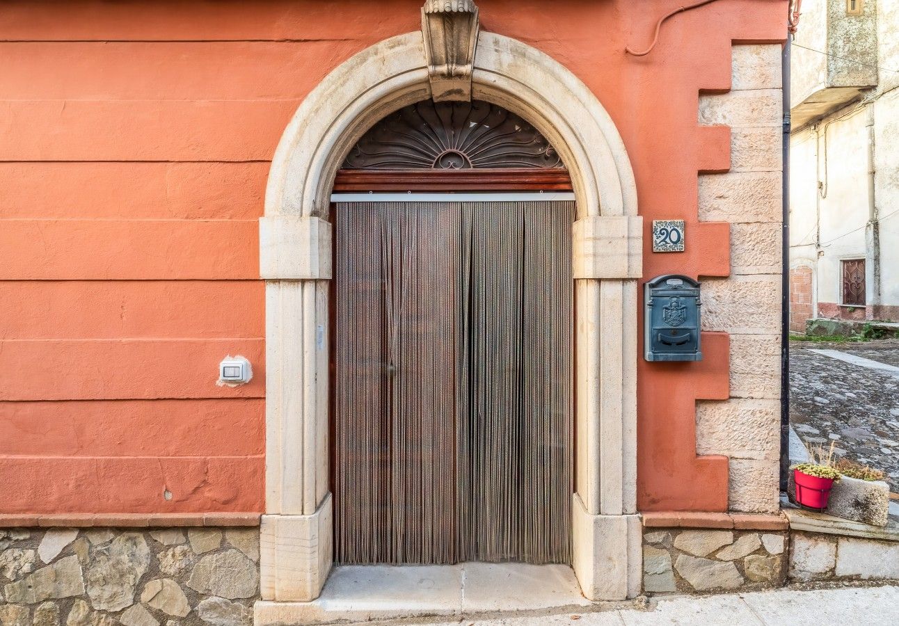 L’entrée d’un immeuble avec une porte en bois, des marches en pierre et une boîte aux lettres.