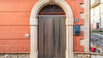 L’entrée d’un immeuble avec une porte en bois, des marches en pierre et une boîte aux lettres.