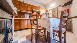 Une cuisine avec des meubles de rangement en bois, une table à manger avec des chaises et un réfrigérateur.