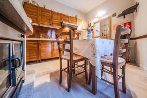 A kitchen with wooden cabinets, a dining table with chairs, and a refrigerator.