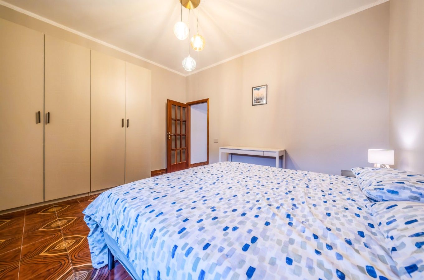 Une chambre à coucher comprenant un lit, une armoire, un bureau et une table de chevet.