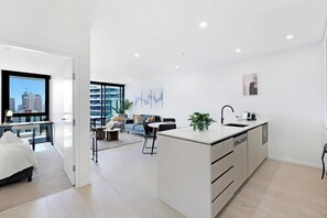 A modern apartment with a kitchen, dining area, and living room. - Ocean View 2BR, Steps to Beach | Pool, Gym Parking (Broadbeach)