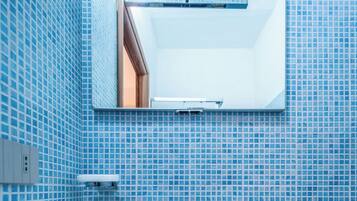 Ein Badezimmer mit Waschbecken, Spiegel und blauen Fliesenwänden.