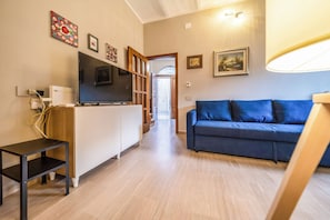 A modern living room with a flat-screen TV, a blue sofa, and a small table. - Casa Bisaccese (Bisaccia)